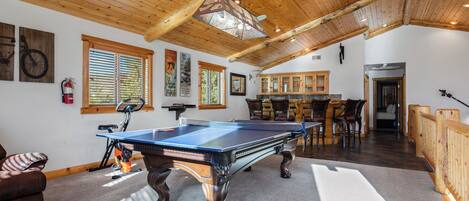 A pool table in a room with wooden ceiling beams, a fire extinguisher, and a bicycle.