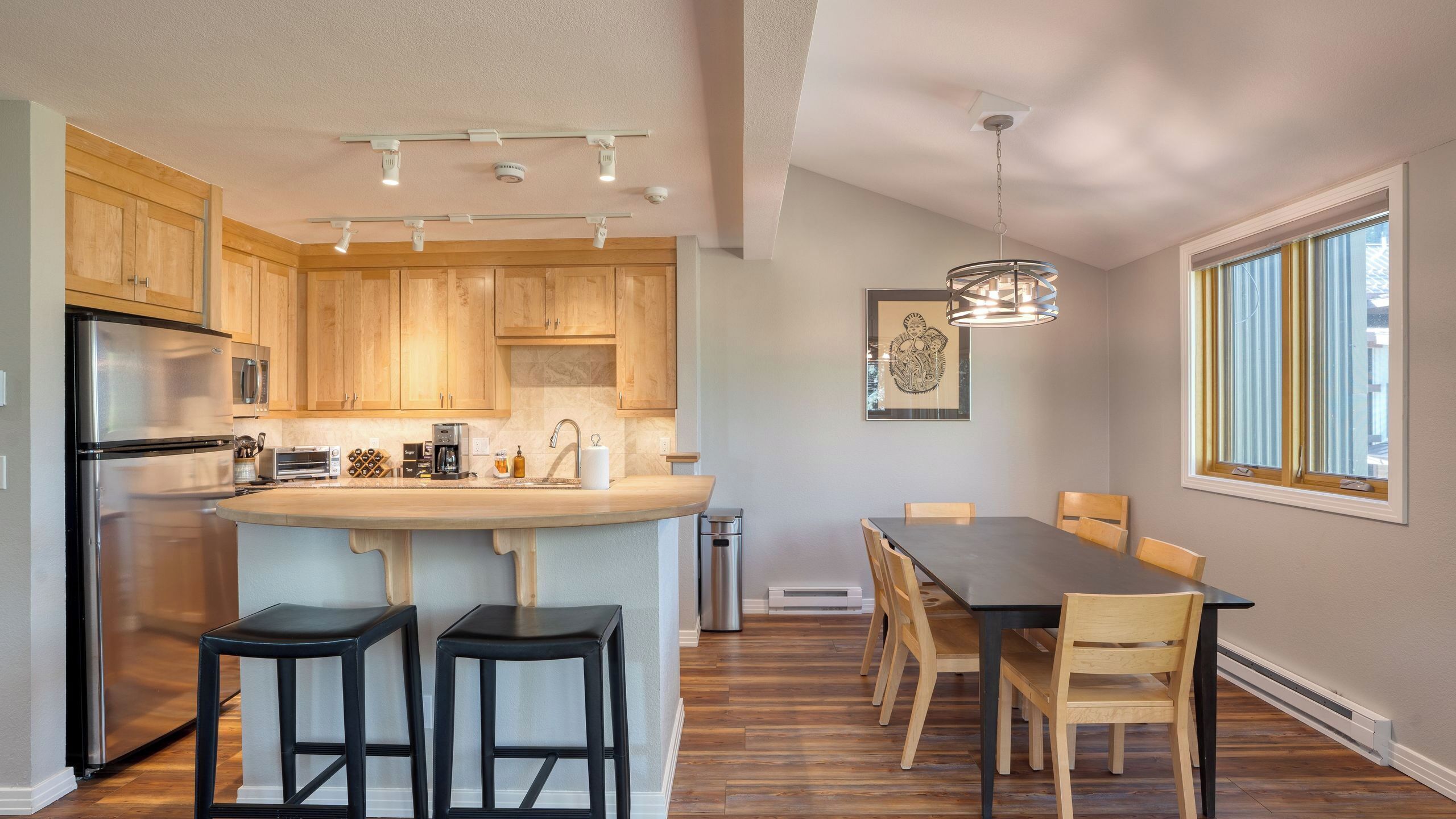 A modern kitchen with wooden cabinets, stainless steel appliances, and a central island with bar stools.