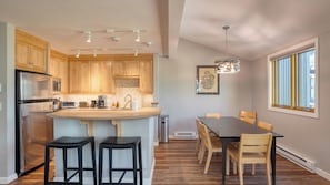 A modern kitchen with wooden cabinets, stainless steel appliances, and a central island with bar stools.