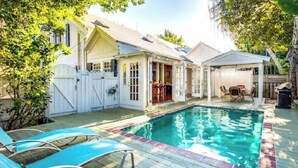 A residential backyard with a swimming pool, a fenced area, and a patio with outdoor furniture.