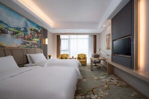 Habitación de hotel con dos camas, un escritorio, una silla, un televisor y un cuadro grande en la pared.