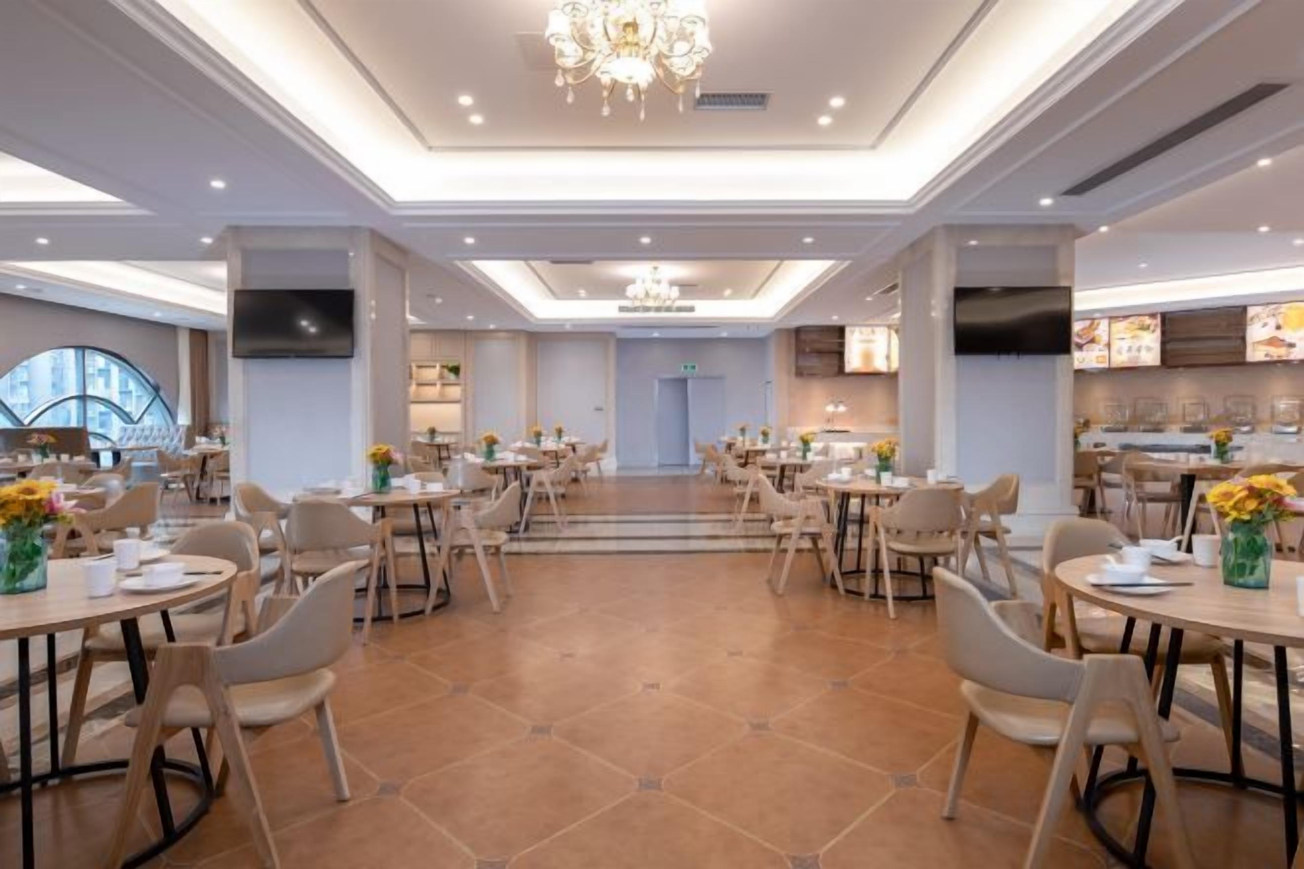 Un comedor amplio con varias mesas y sillas, un candelabro central y una decoración de estilo moderno.