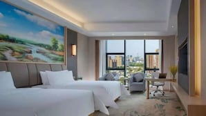 A hotel room with two beds, a desk, a chair, a TV, and a large window with a city view.