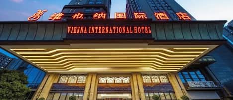 A hotel with a prominent entrance, large windows, and a sign indicating it is the Vienna International Hotel.