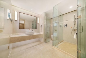 Un baño moderno con cabina de ducha de vidrio, un espejo grande y un tocador de mármol.