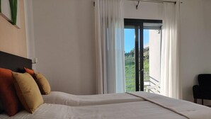 A bedroom with two beds, a view of a balcony, and a chair. - Casa Ceedina Bed and Breakfast & Beauty (Batalha)