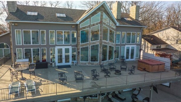 Un bâtiment à deux étages doté de grandes fenêtres et d’un patio couvert aménagé avec du mobilier d’extérieur.