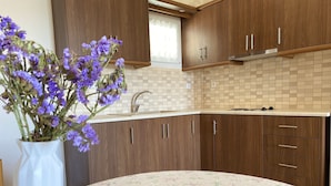 A kitchen with wooden cabinets, a sink, and a vase with purple flowers. - Armonia - Elegant Apartments (Mantoudi-Limni-Agia Anna)