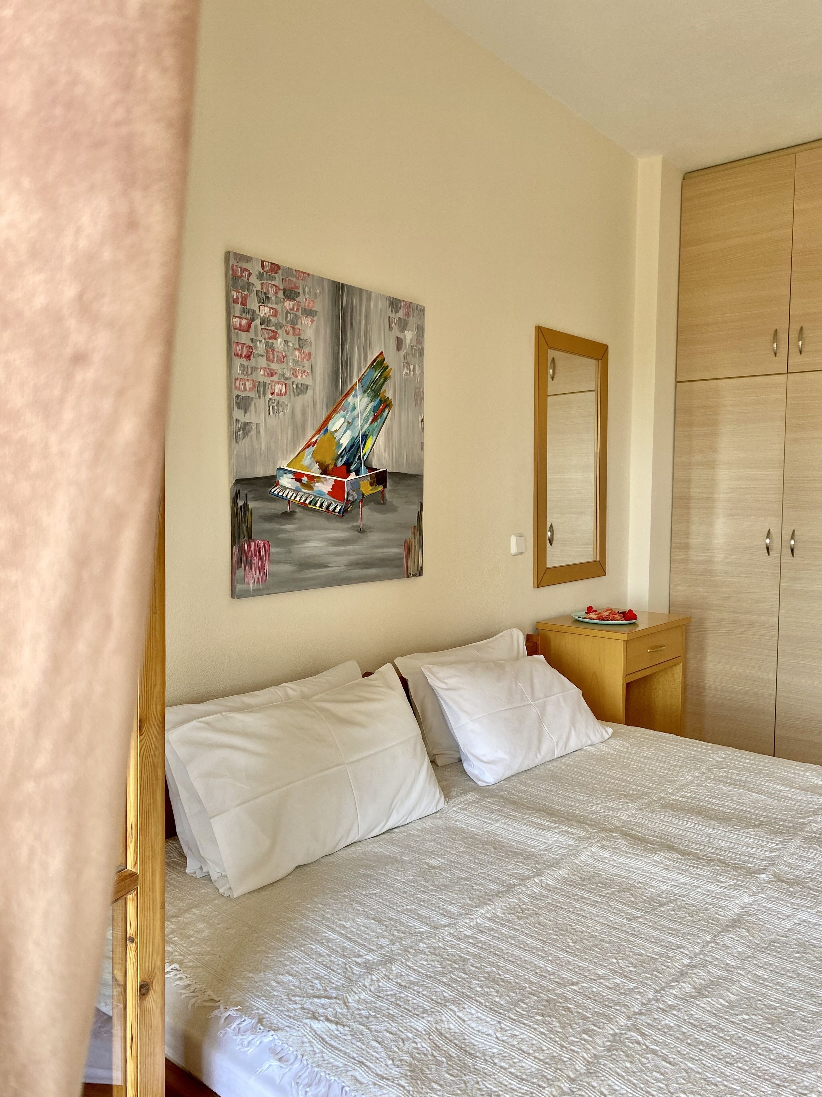 A bedroom with a bed, a wooden nightstand, a mirror, and a wardrobe.