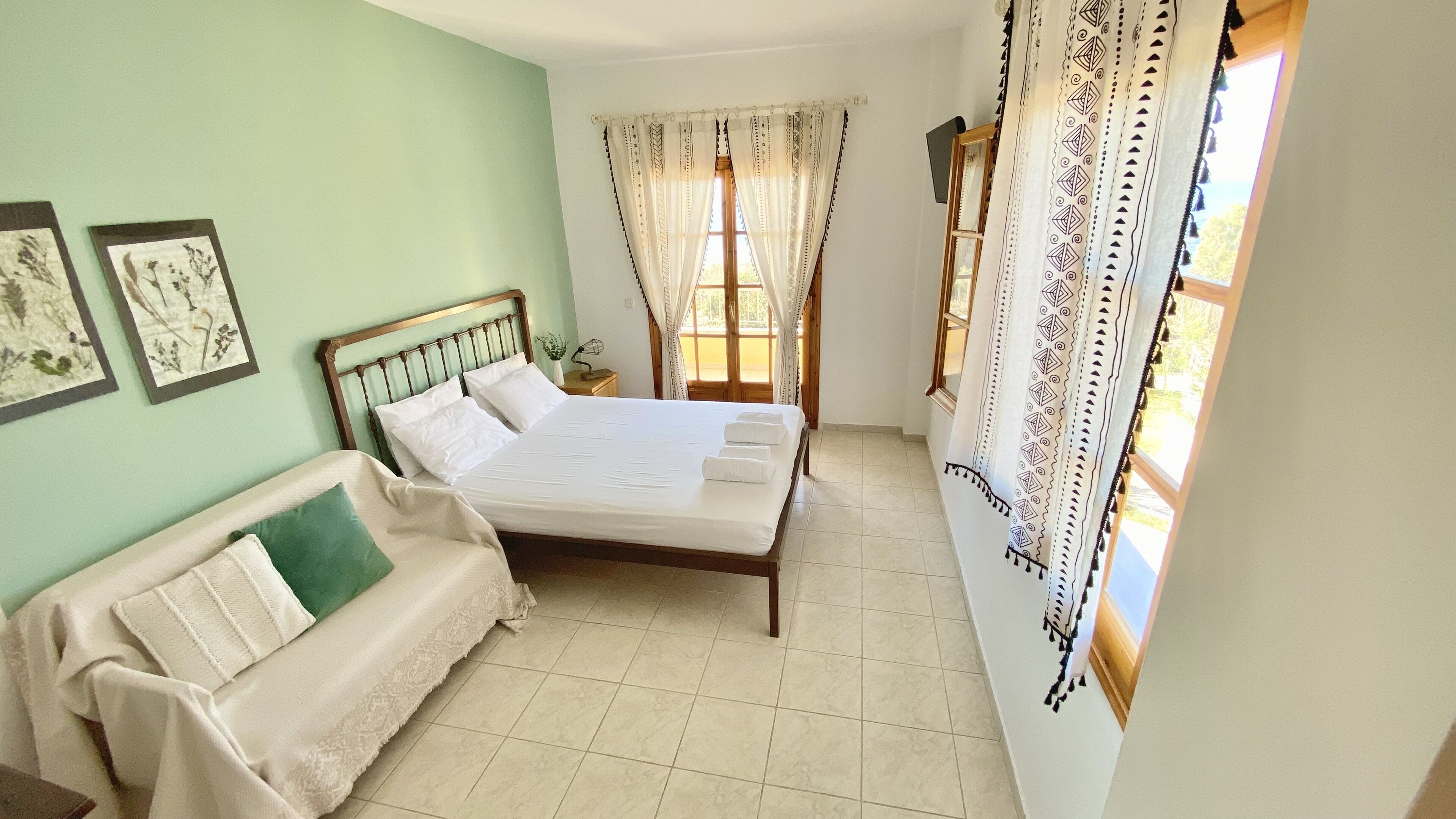 A bedroom with a bed, a bedside table, a chair, and a window with curtains.