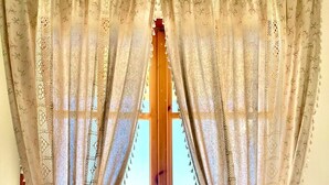 A breakfast tray with pastries, a glass of orange juice, and a cup of coffee on a table by a window with lace curtains. - Armonia - Elegant Apartments (Mantoudi-Limni-Agia Anna)