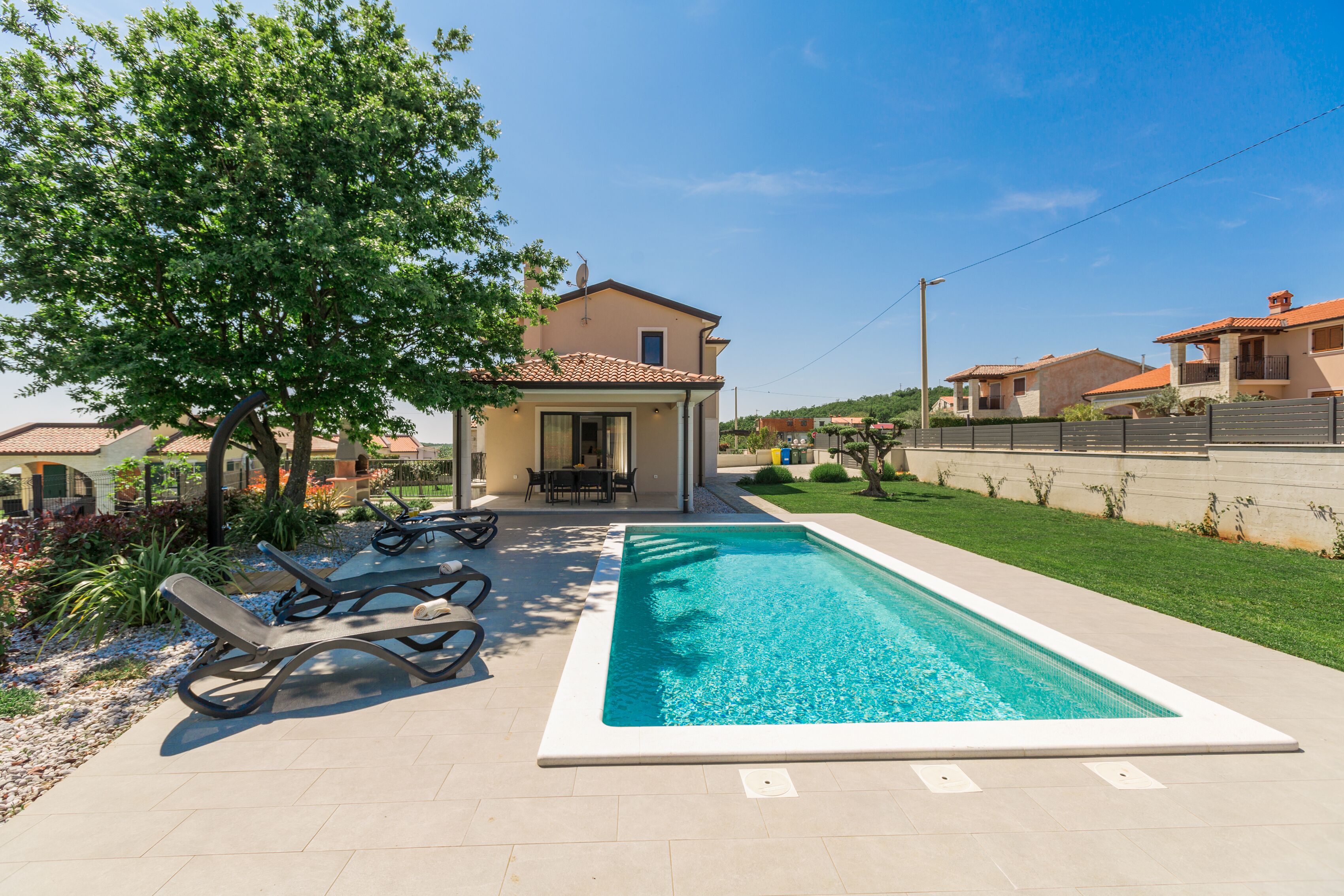 A swimming pool with lounge chairs, a small building, and a well-maintained lawn.