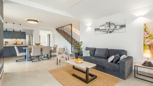 A modern living room with a grey sofa, a coffee table, and a staircase leading to an upper floor. - Villa for 4-6 people, pool, loungers, garden, panoramic sea view (Poreč)
