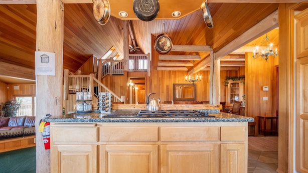 Une cuisine spacieuse avec des meubles en bois, un grand îlot central et un ventilateur de plafond.