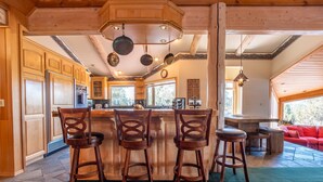 Une cuisine avec des meubles en bois, un coin bar avec des tabourets et un canapé rouge dans l’espace salon.