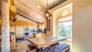 Une cuisine spacieuse avec des meubles de rangement en bois, une grande table en bois et un banc.