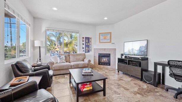 A modern living room with a fireplace, leather sofas, a coffee table, and a TV.