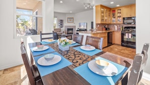 A spacious dining area with a large table set for four, surrounded by wooden chairs.