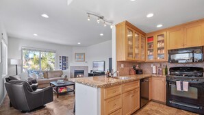A modern kitchen with wooden cabinets, a granite countertop, and a black stove.