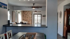 A spacious kitchen with a long counter, a dining table with chairs, and a ceiling fan.
