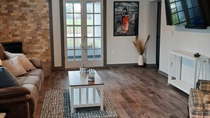 A living room with a brown leather couch, a white coffee table, and a ceiling fan.