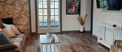 Un salon avec un canapé en cuir marron, une table basse blanche et un ventilateur de plafond.
