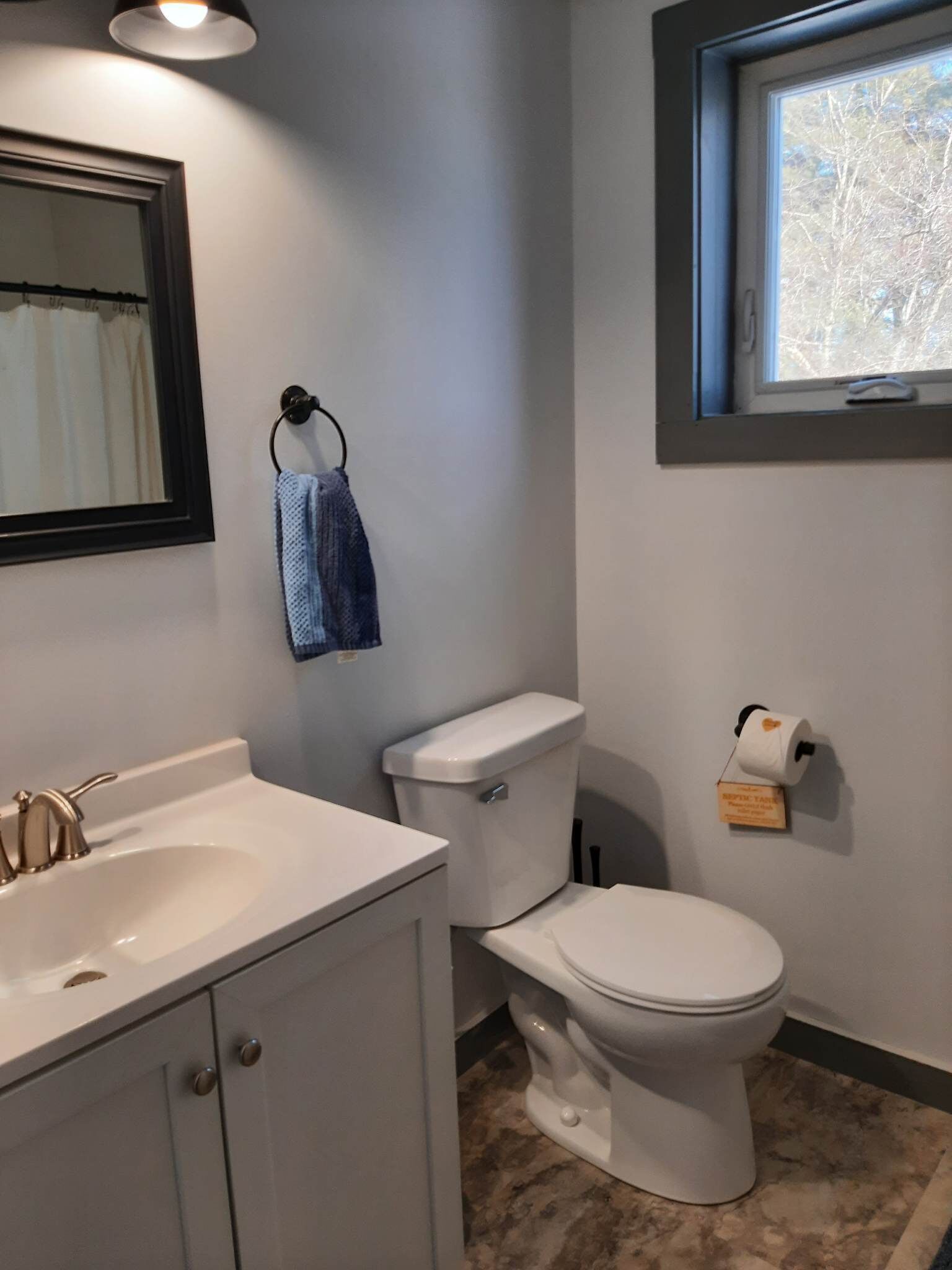 A bathroom with a white sink, a toilet, and a window above the toilet.