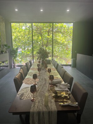 A long dining table with chairs, wine glasses, and a centerpiece.