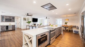 Eine moderne Küche mit einer zentralen Kochinsel, eingebauten Backöfen und einem Essbereich mit Holztisch und Stühlen.