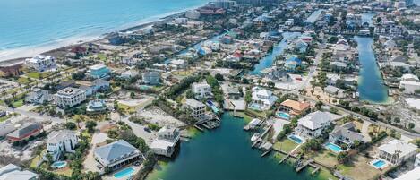 An aerial view of a coastal residential area with houses, a marina, and a beach.