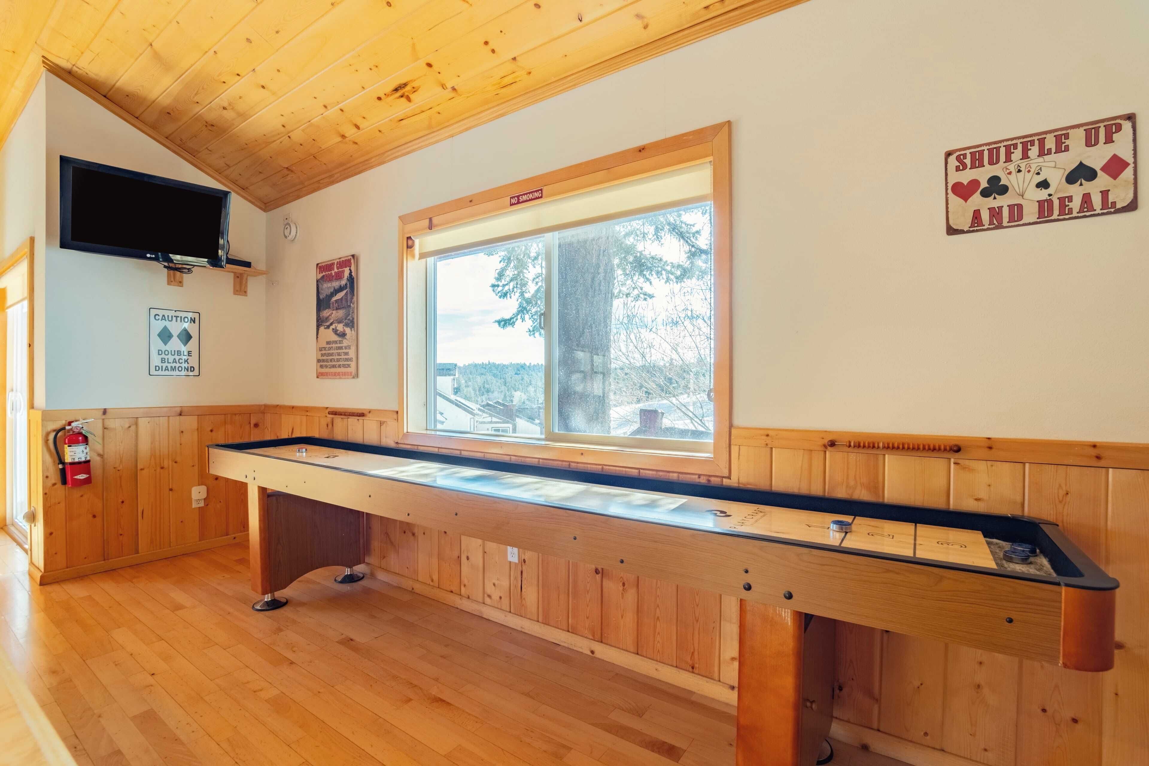 Una mesa de billar en una habitación con paredes de madera y una ventana.