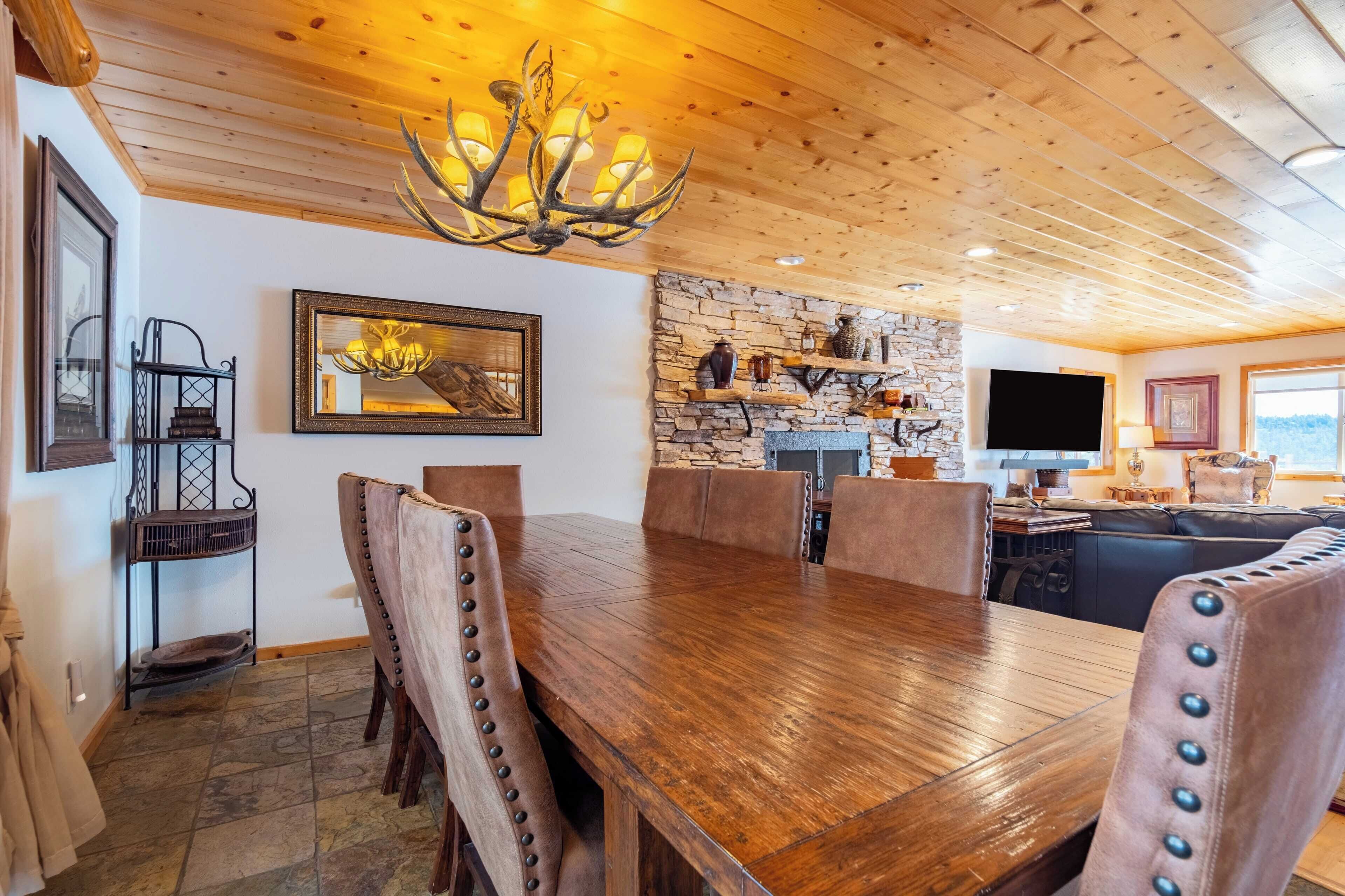 Ein Holzespeisesaal mit sechs Stühlen, einem Steinkamin und einem Fernseher an einer Steinsäule.
