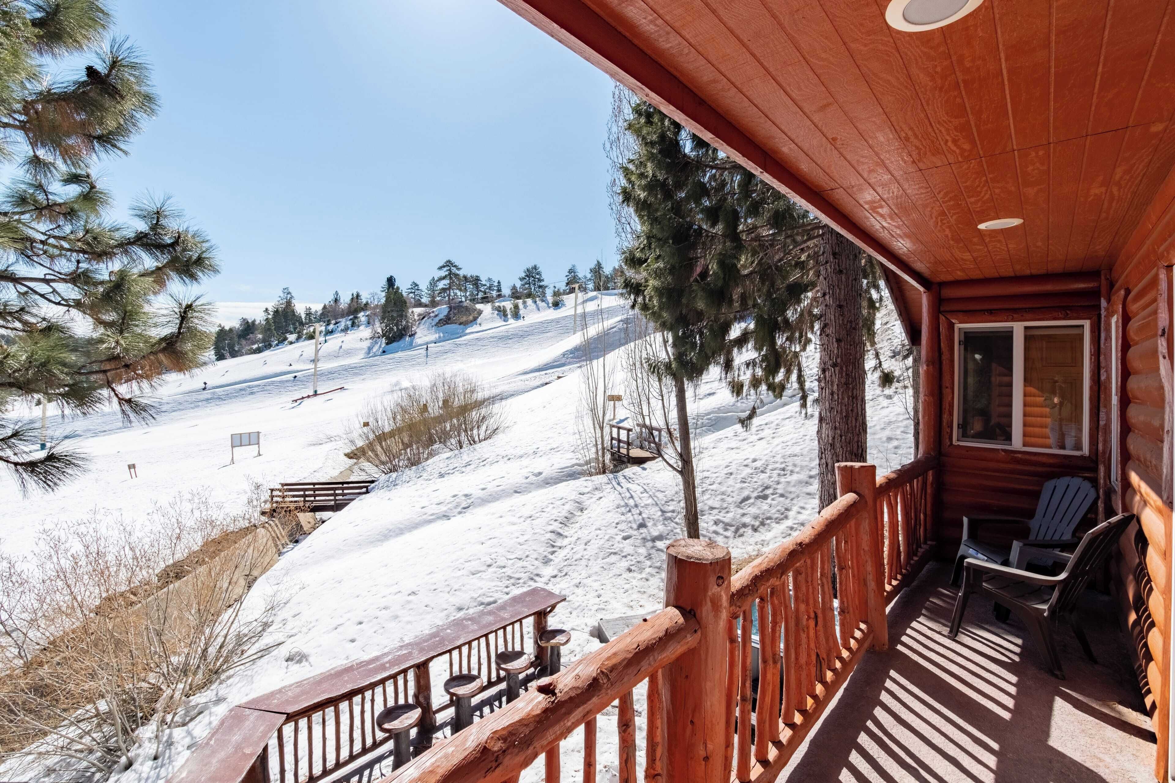 A wooden cabin with a porch overlooking a snowy landscape.