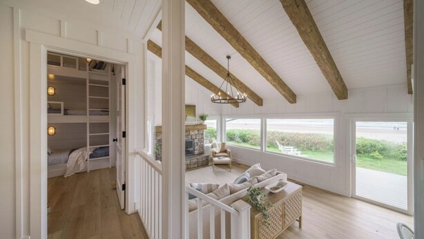 A spacious room with a high ceiling, built-in shelving, a fireplace, and large windows offering a view of the outdoors. - Oceanfront w/ Direct Beach Access Game Room Views Driftaway by Avantstay (Cannon Beach)