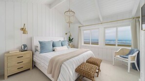 A bedroom with a bed, bedside tables, a chair, a view of the ocean, and a hanging light fixture. - Oceanfront w/ Direct Beach Access Game Room Views Driftaway by Avantstay (Cannon Beach)