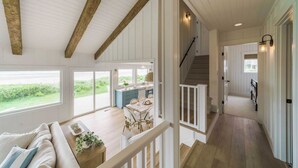 A spacious interior with a wooden ceiling, a dining area with a table and chairs, and a view through large windows. - Oceanfront w/ Direct Beach Access Game Room Views Driftaway by Avantstay (Cannon Beach)