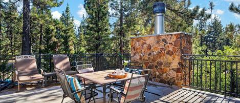 An outdoor patio with a stone wall, metal railing, and a table with chairs.
