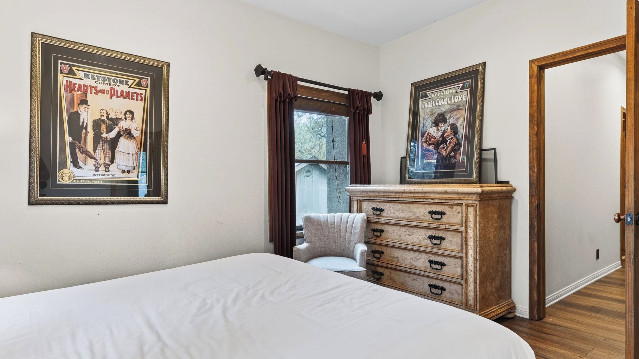 A bedroom with a bed, a dresser, and two framed posters on the wall.