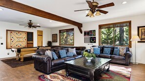 A spacious living room with a pool table, leather sofas, and a ceiling fan. - Walk to Lake 6BR Cabin w/ Game Room, Hot Tub Big Bear Castle (Big Bear Lake)