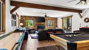 Ein großzügiger Wohnbereich mit Poolbillard, Kamin und einer Couch.