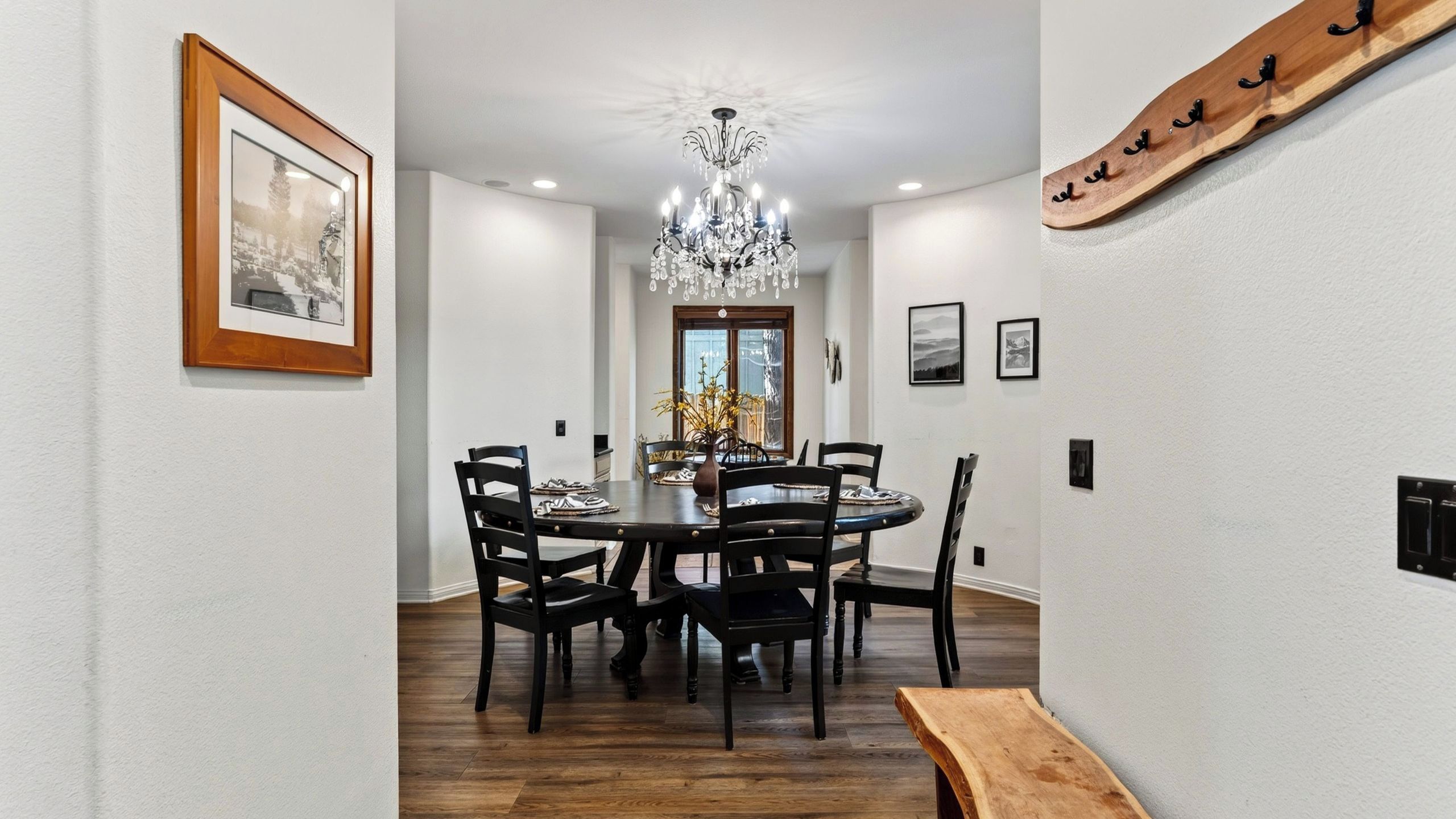 Un coin repas avec une table ronde, des chaises, un lustre et des tableaux encadrés accrochés aux murs.