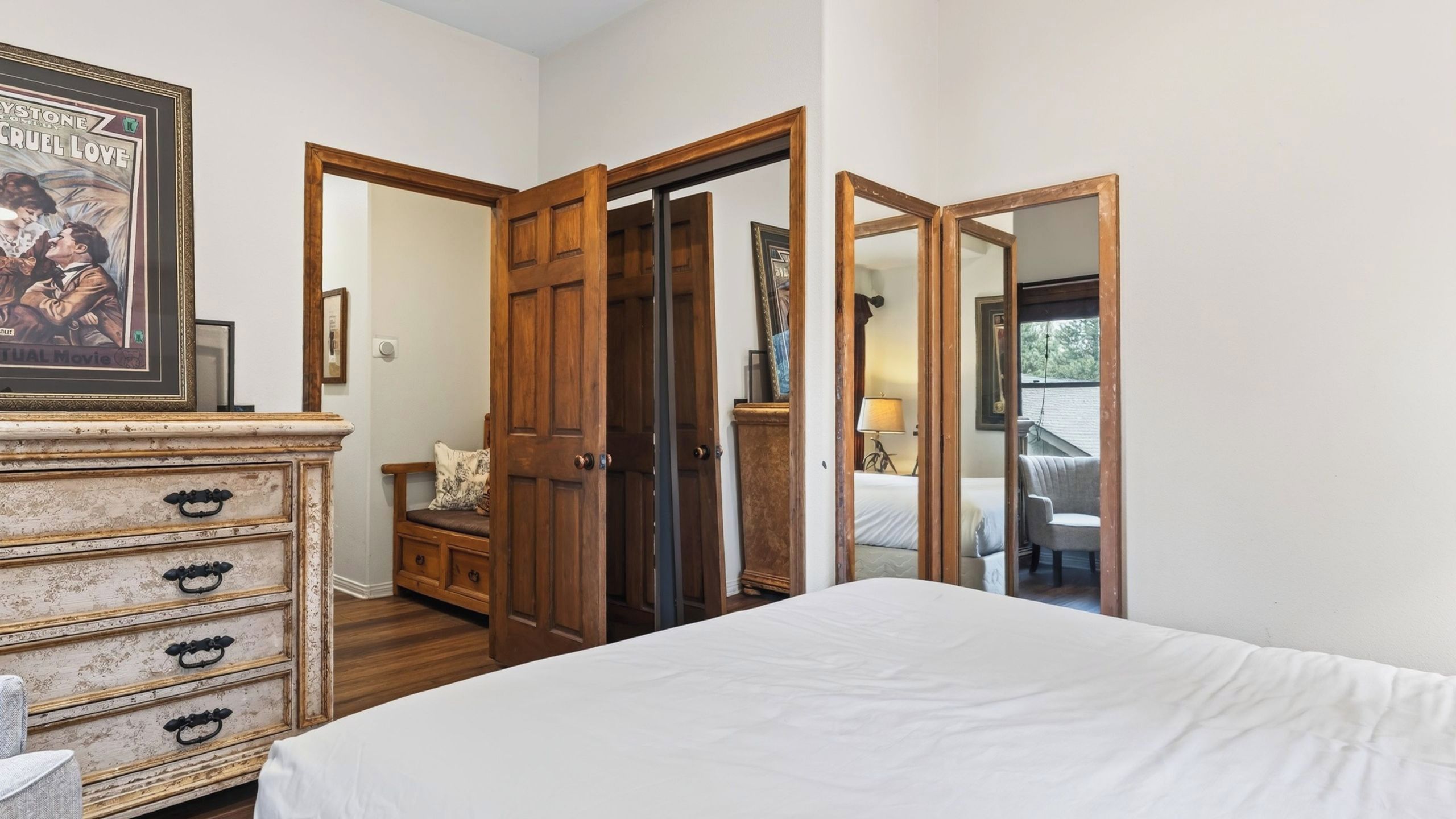 A bedroom with a bed, dresser, and a door leading to another room.