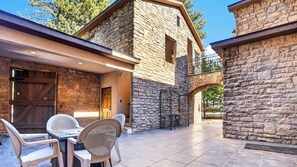 A stone building with a patio area featuring a table and chairs. - Walk to Lake 6BR Cabin w/ Game Room, Hot Tub Big Bear Castle (Big Bear Lake)