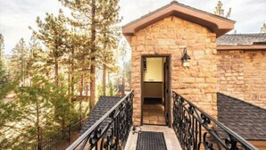 A stone building with a wooden door, surrounded by trees. - Walk to Lake 6BR Cabin w/ Game Room, Hot Tub Big Bear Castle (Big Bear Lake)
