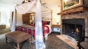 A bedroom with a four-poster bed, a fireplace, and a ceiling fan. - Walk to Lake 6BR Cabin w/ Game Room, Hot Tub Big Bear Castle (Big Bear Lake)