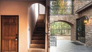 A stone staircase leading to a second-floor balcony with a wrought iron railing. - Walk to Lake 6BR Cabin w/ Game Room, Hot Tub Big Bear Castle (Big Bear Lake)