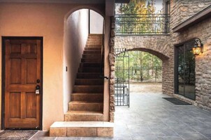 A stone staircase leading to a second-floor balcony with a wrought iron railing.