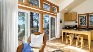 A modern kitchen with wooden cabinets, a dining table, and bar stools. - Coastal Getaway in Manzanita w Fire Pit, Guest House & Views Seagrove by Avantstay (Manzanita)