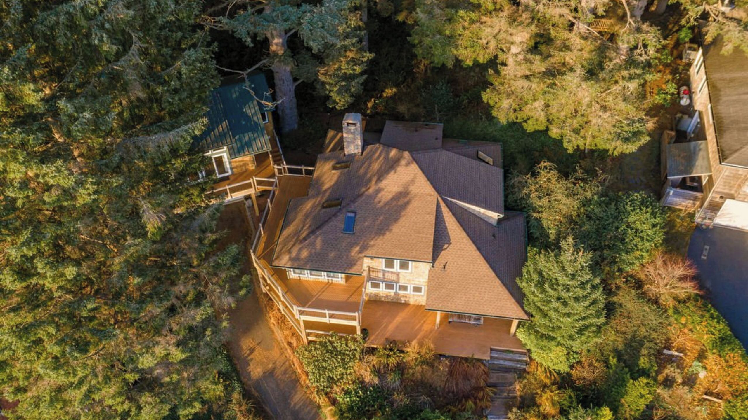 Ein Haus mit geneigtem Dach, einem sichtbaren Schornstein und einer Terrassenfläche.