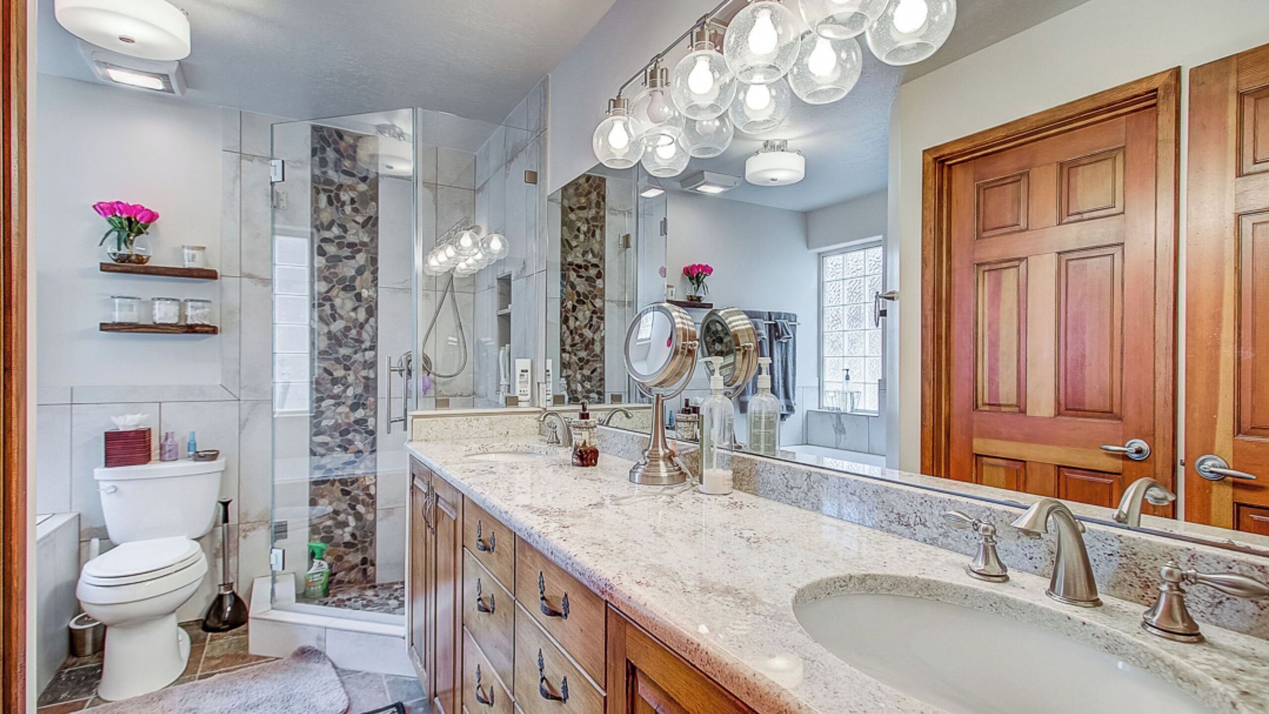 Une salle de bain moderne avec un grand miroir, une douche et un lavabo.